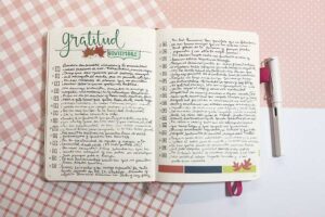 un cuaderno bullet journal abierto que muestra frases de gratitud de un mes