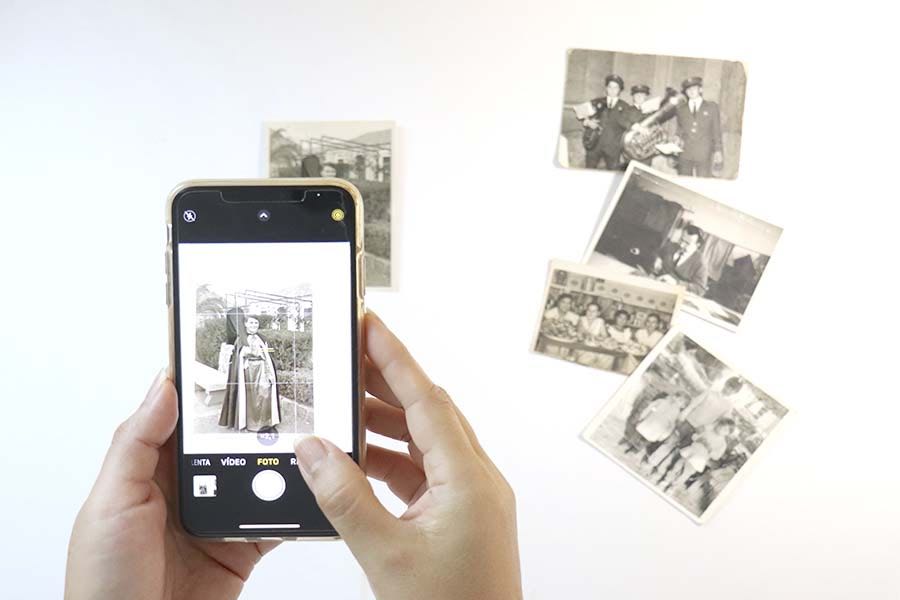 una mano sostiene un movil mientras toma una foto antigua para digitalizarla